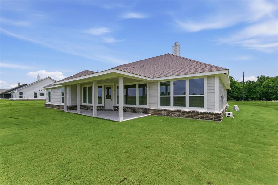 Spacious backyard featuring a covered patio, extensive lawn, multi-pane windows, and a brick and siding exterior Spacious backyard featuring a covered patio, extensive lawn, multi-pane windows, and a brick and siding exterior