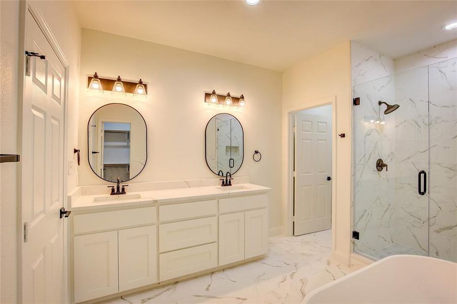 Bathroom featuring marble look tile flooring, a marble finish shower, double vanity, recessed lighting, and a freestanding tub Bathroom featuring marble look tile flooring, a marble finish shower, double vanity, recessed lighting, and a freestanding tub