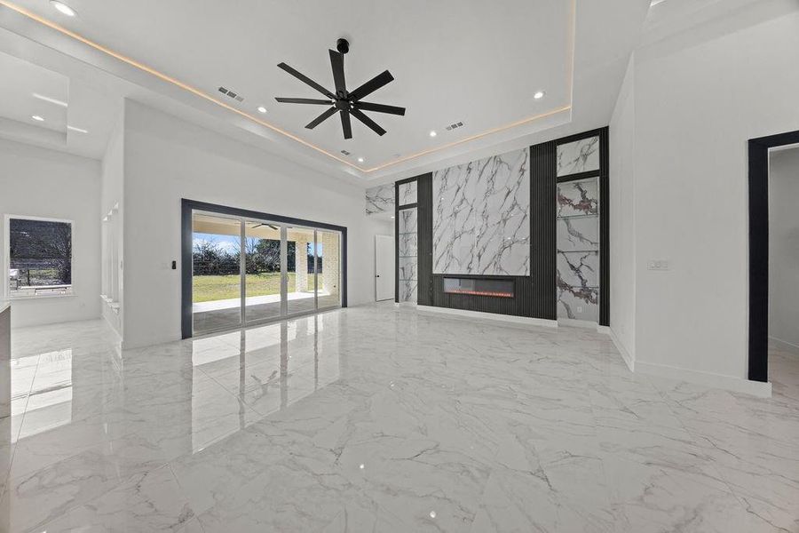 Unfurnished living room featuring recessed lighting, an accent wall, light marble finish floors, ceiling fan, and a premium fireplace