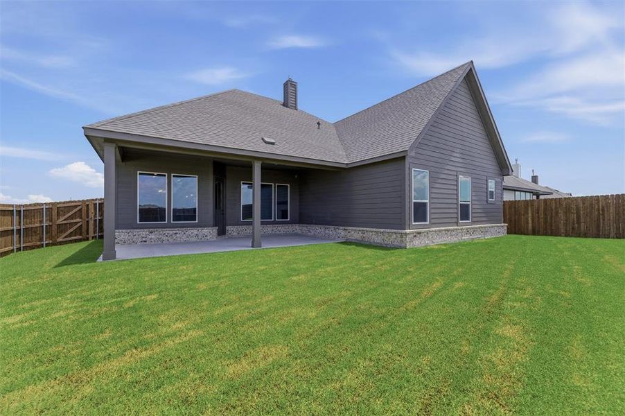 Expansive backyard featuring a covered concrete patio, wood privacy fencing, and a manicured lawn Expansive backyard featuring a covered concrete patio, wood privacy fencing, and a manicured lawn