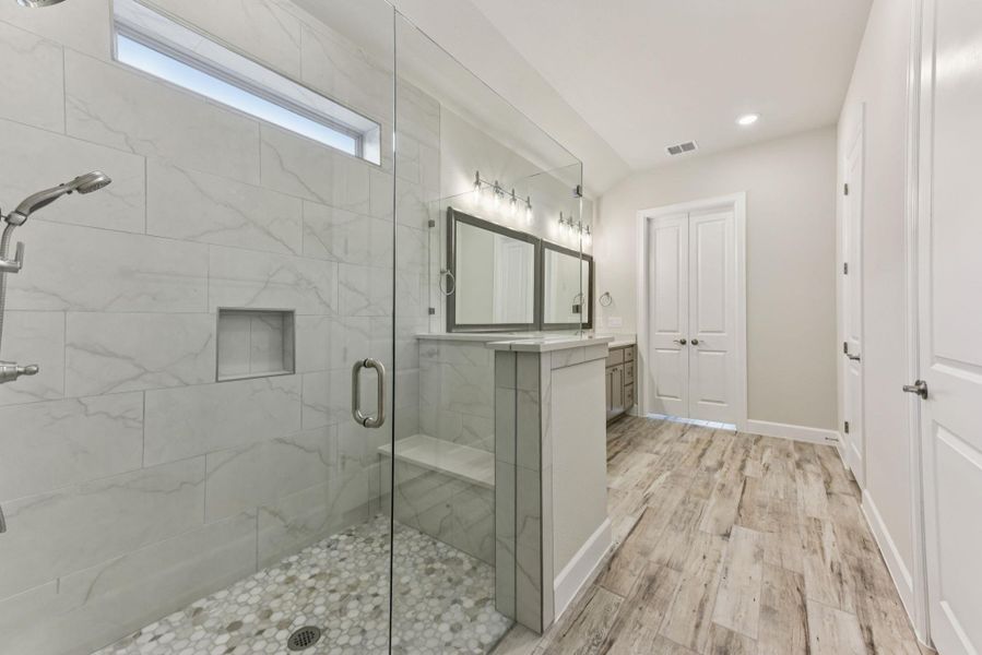 Full bath with vanity, light wood-type flooring, a marble finish shower, and recessed lighting