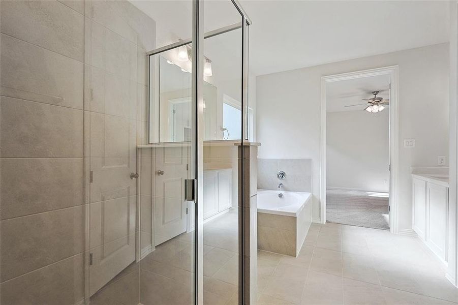 Bathroom with tile patterned floors, plus walk in shower, vanity, and ceiling fan