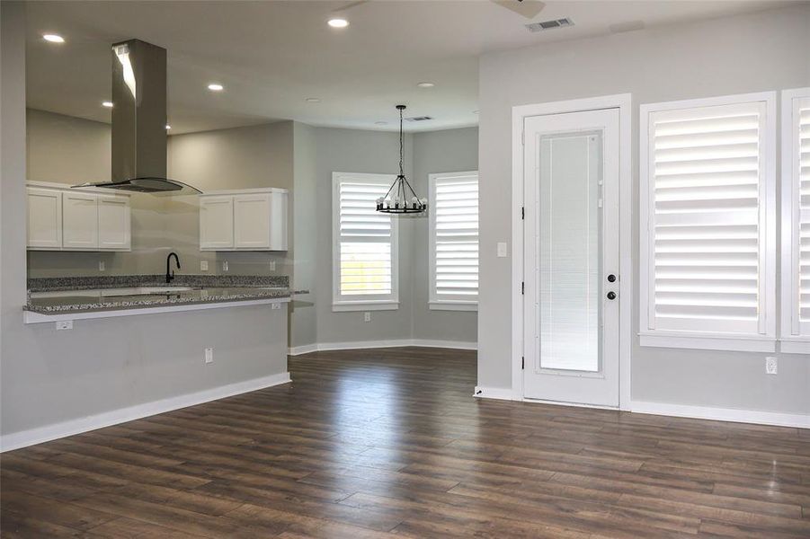 Kitchen with island range hood, dark wood finished floors, white cabinetry, recessed lighting, and pendant lighting Kitchen with island range hood, dark wood finished floors, white cabinetry, recessed lighting, and pendant lighting