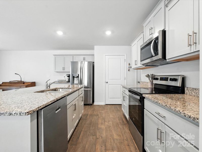 Well-designed kitchen features white  and grey shaker-style cabinets, granite countertops, and stainless steel appliances. Ample counter space and storage with convenient pantry access make this a chef's delight.
