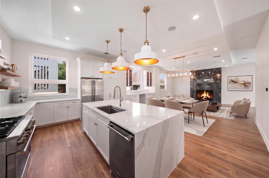 Virtually Staged - Alternate kitchen view showcasing white cabinetry, quartz countertops, stainless steel appliances, and an open concept to the living and dining areas. Virtually Staged - Alternate kitchen view showcasing white cabinetry, quartz countertops, stainless steel appliances, and an open concept to the living and dining areas.