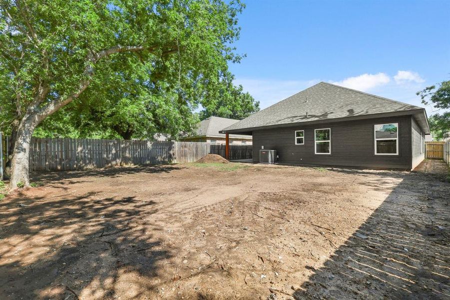 Rear view of property with central AC, a fenced backyard, and a shingled roof