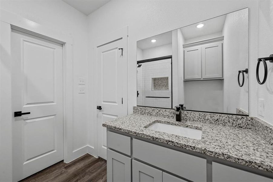 Bathroom with vanity, wood-type flooring, and a shower with shower door