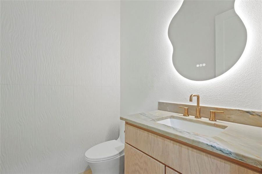 Bathroom featuring vanity and a textured wall Bathroom featuring vanity and a textured wall