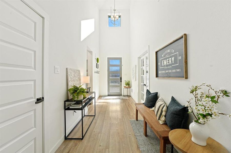 Foyer featuring a towering ceiling, light wood-type flooring, and a chandelier