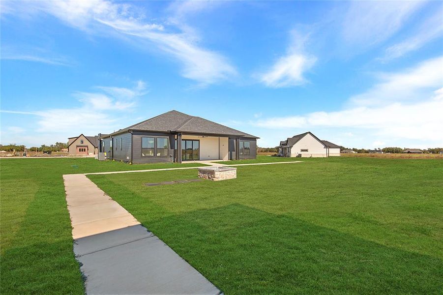 Back of property featuring a lawn, an outdoor fire pit, and roof with shingles Back of property featuring a lawn, an outdoor fire pit, and roof with shingles