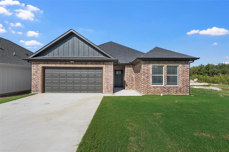 View of front of house with concrete driveway, a front yard, an attached garage, board and batten siding, and roof with shingles View of front of house with concrete driveway, a front yard, an attached garage, board and batten siding, and roof with shingles