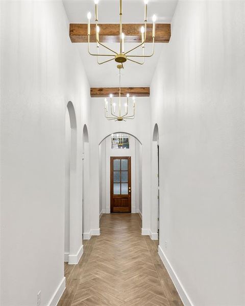 Hallway featuring herringbone wood-finish flooring, white walls, and arched doorways