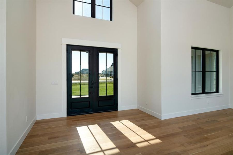 Foyer with french doors, high vaulted ceiling, and light hardwood / wood-style flooring