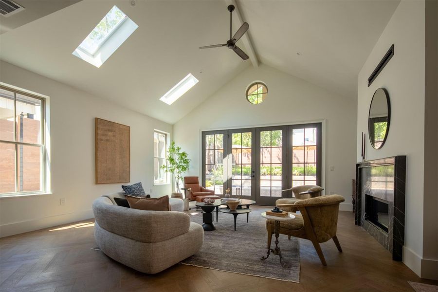 Vaulted ceilings with skylights and patterned wood floors elevate this elegant living space. Vaulted ceilings with skylights and patterned wood floors elevate this elegant living space.