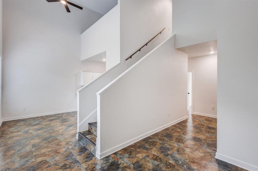 Staircase featuring ceiling fan, dark tile patterned floors, and a towering ceiling