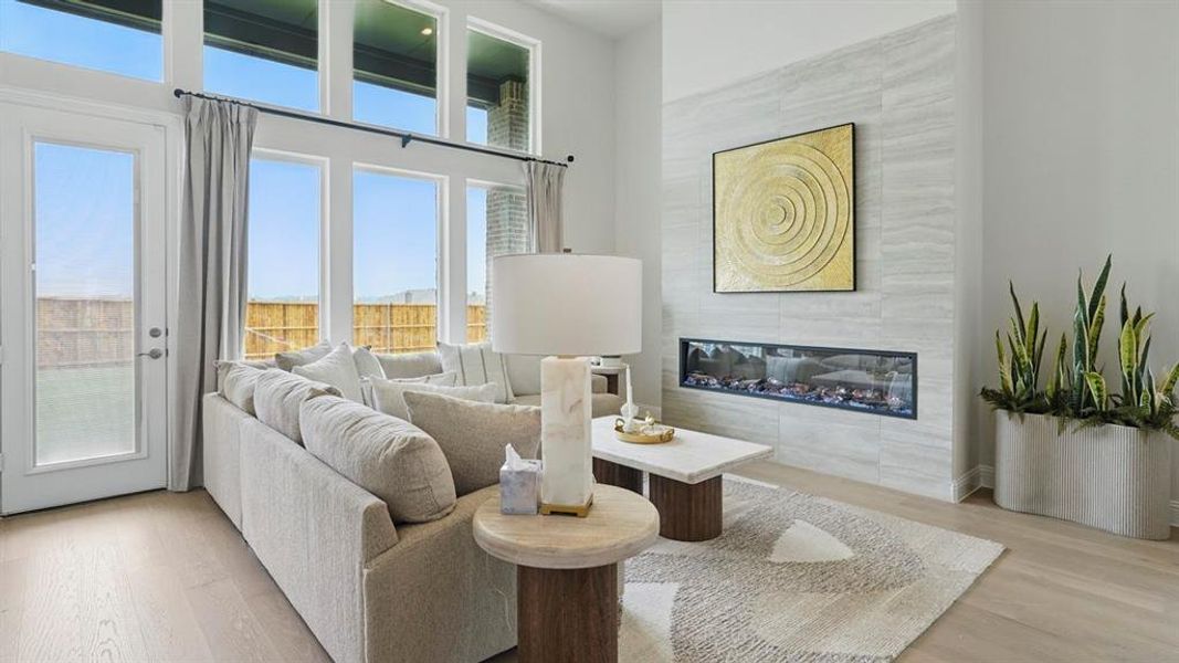 Living area with a fireplace, light wood-style flooring, and a high ceiling
