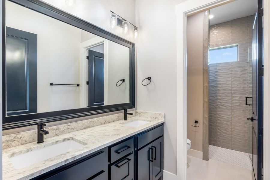 Bathroom featuring vanity, toilet, and a tile shower