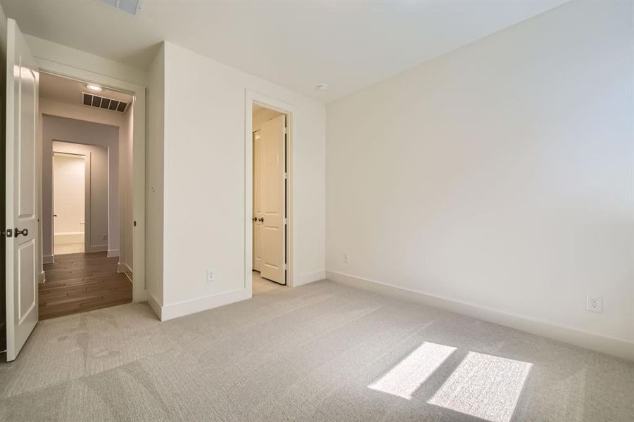 Unfurnished bedroom featuring light carpet, visible vents, and baseboards