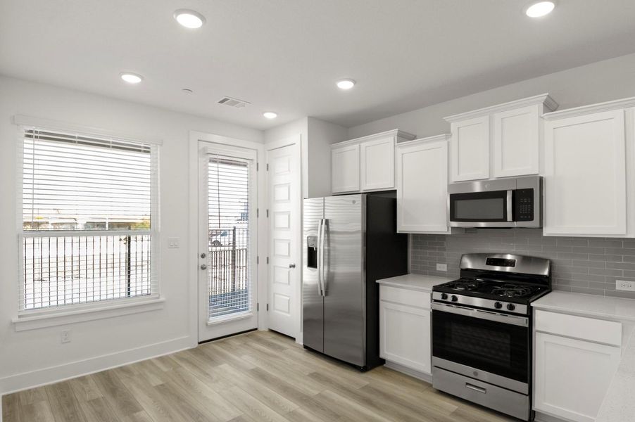 Kitchen featuring stainless steel appliances, white cabinets, light wood-style floors, backsplash, and recessed lighting