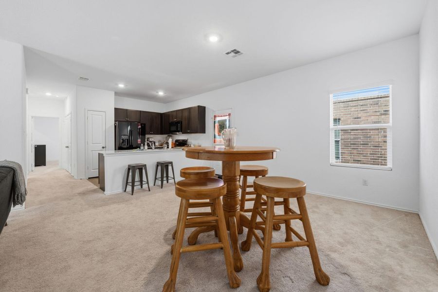 Open-concept living space with light-toned carpeting and neutral wall finishes
