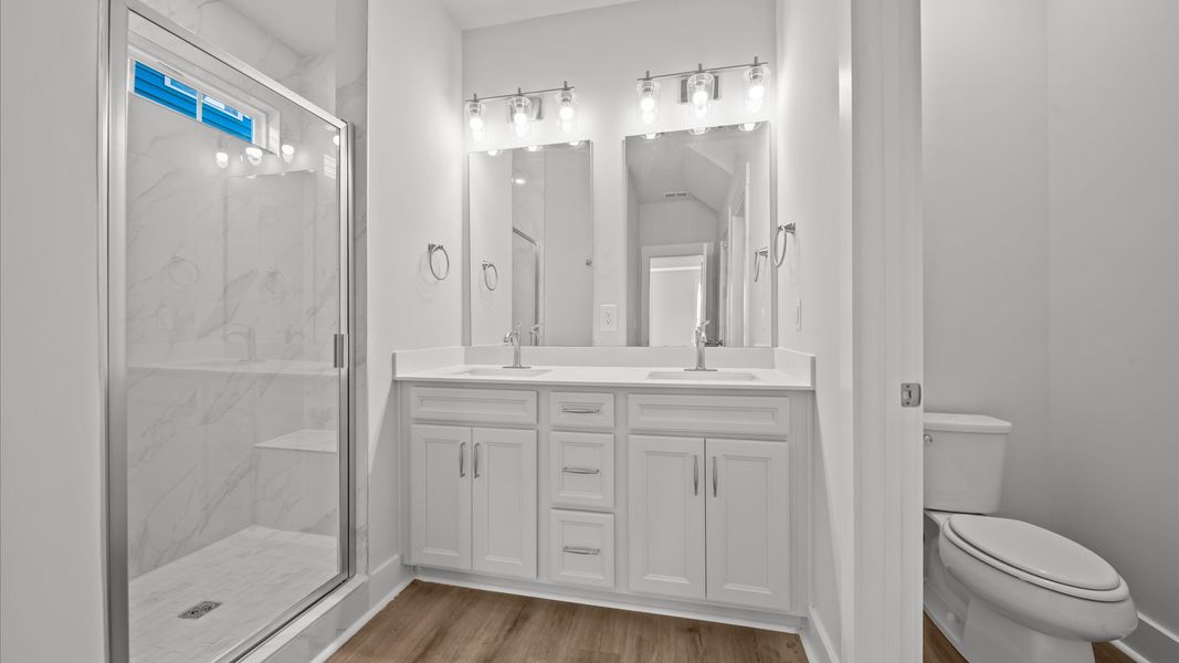 Accomplished design shines in this primary bath with dual vanity and a sleek tiled walk-in shower