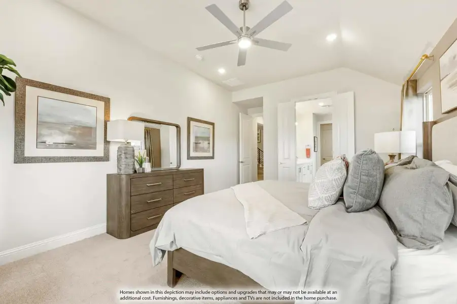 Master bedroom with vaulted ceiling, ceiling fan, carpet flooring, and ensuite bathroom doorway visible in background.