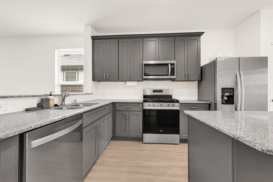 Bright and modern kitchen equipped with extensive countertop space and ample cabinetry.