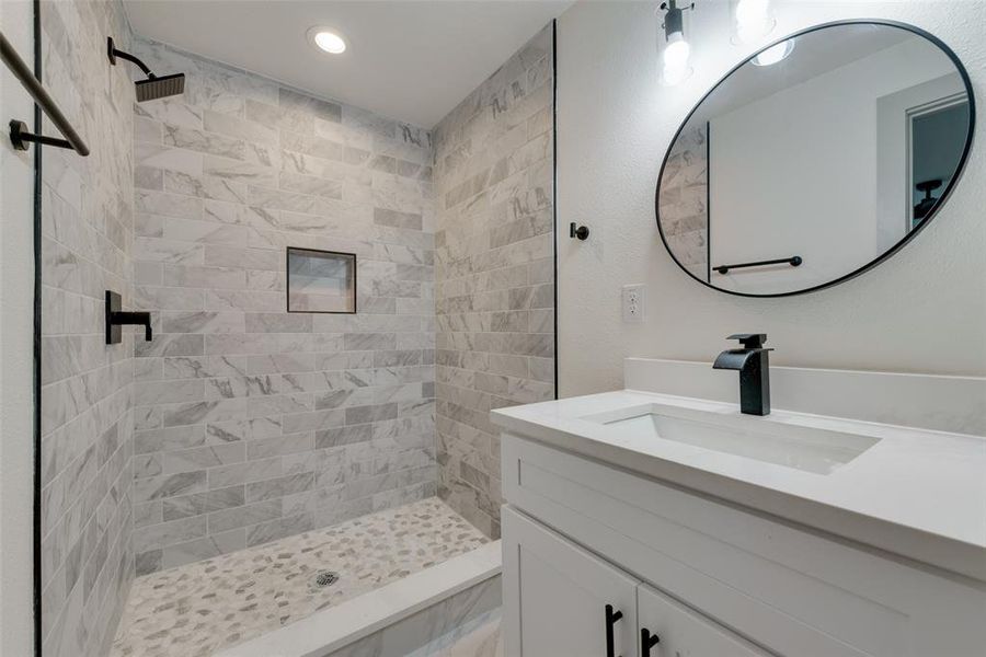 Bathroom with tiled shower and vanity