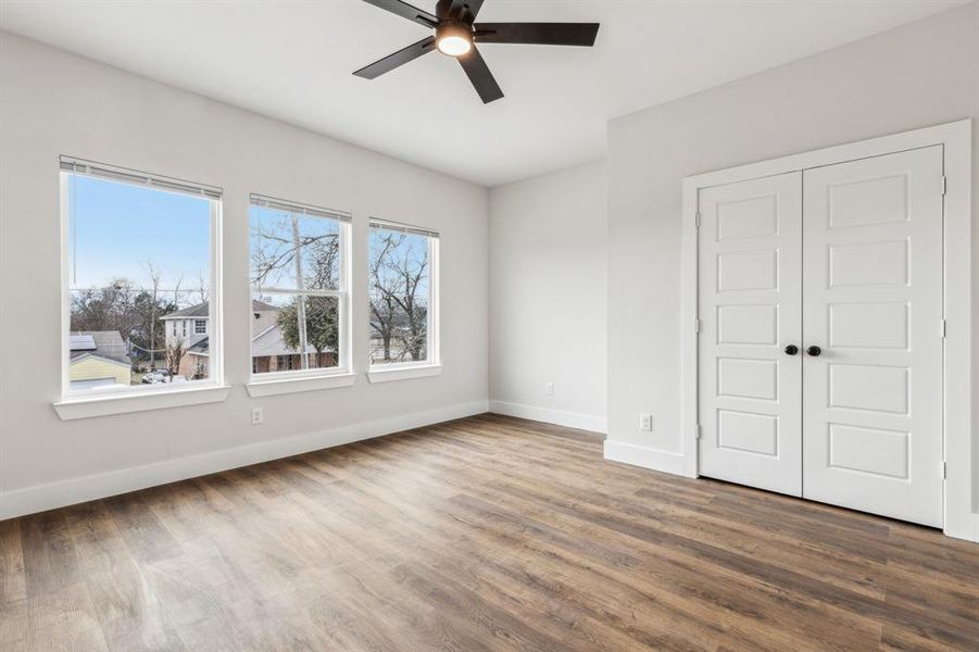 Unfurnished bedroom featuring ceiling fan, a closet, hardwood / wood-style flooring, and multiple windows