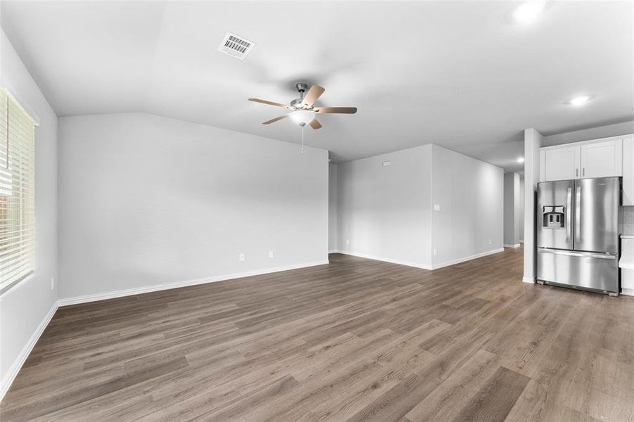 Unfurnished living room with ceiling fan, wood finished floors, recessed lighting, and lofted ceiling Unfurnished living room with ceiling fan, wood finished floors, recessed lighting, and lofted ceiling