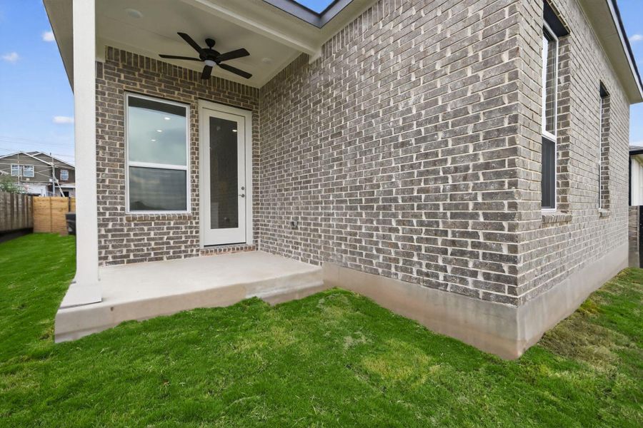 Property entrance featuring brick siding, ceiling fan, and a patio