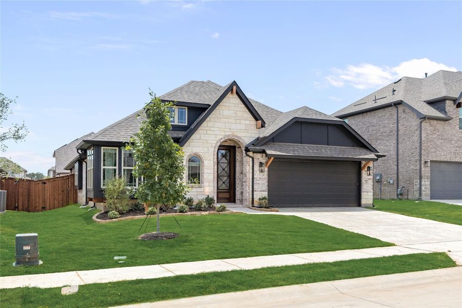 Single-story home with stone and brick exterior, arched entry, two-car garage, and manicured front lawn.