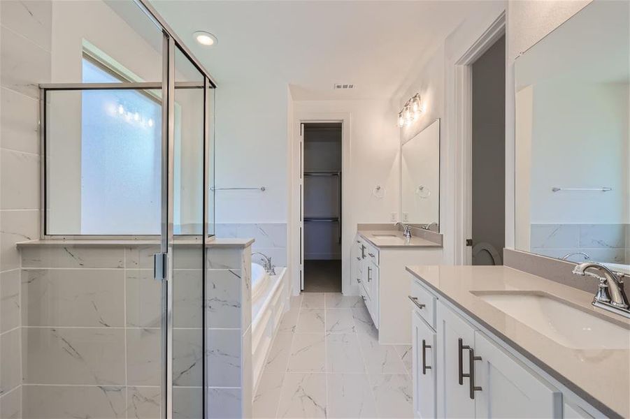 Bathroom featuring tile flooring, dual vanity, and shower with separate bathtub