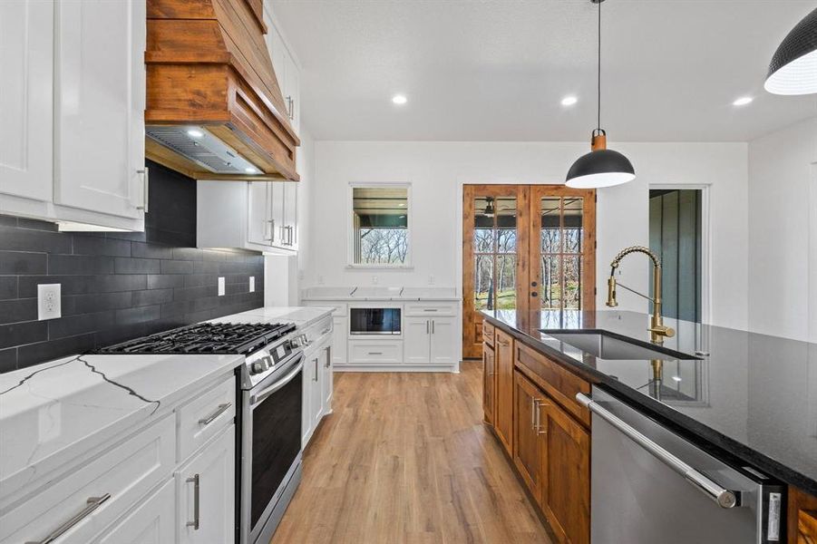 Kitchen featuring white cabinetry, dark stone countertops, and stainless steel appliances