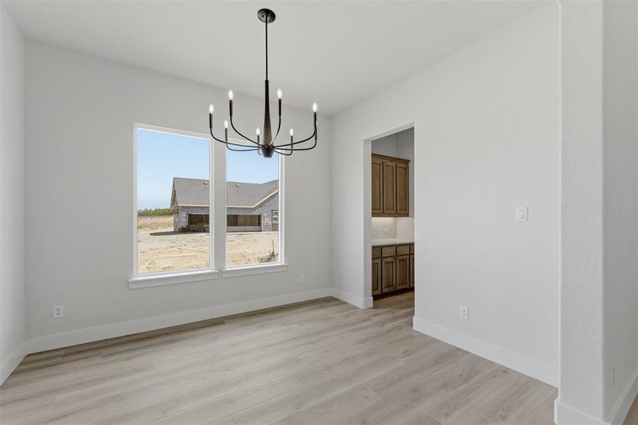 Unfurnished dining area with hanging lights and light wood finished floors