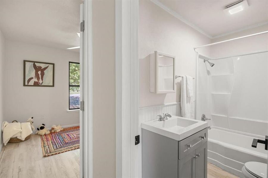 Full bathroom with toilet, crown molding, vanity, shower / tub combination, and hardwood / wood-style flooring