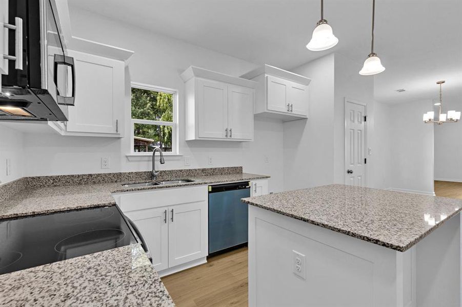 Kitchen featuring a center island, light wood finished floors, white cabinets, and pendant lighting Kitchen featuring a center island, light wood finished floors, white cabinets, and pendant lighting