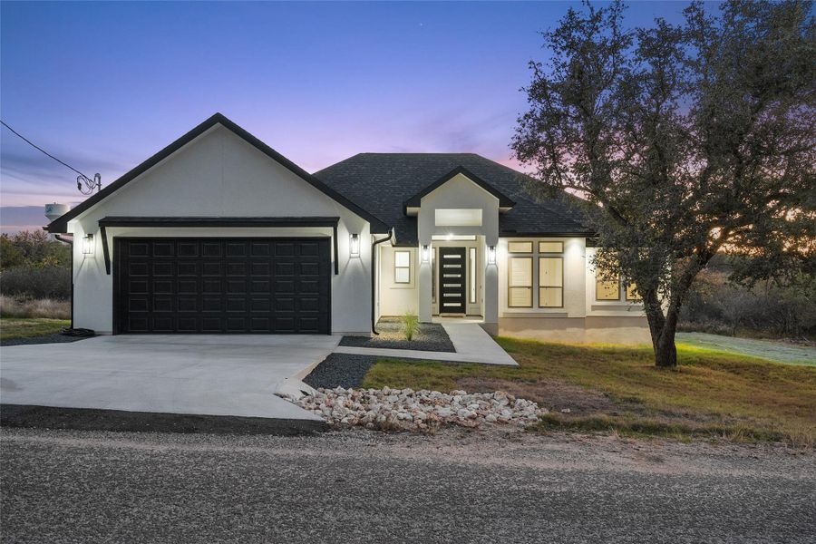 View of front facade with driveway, stucco siding, and a garage