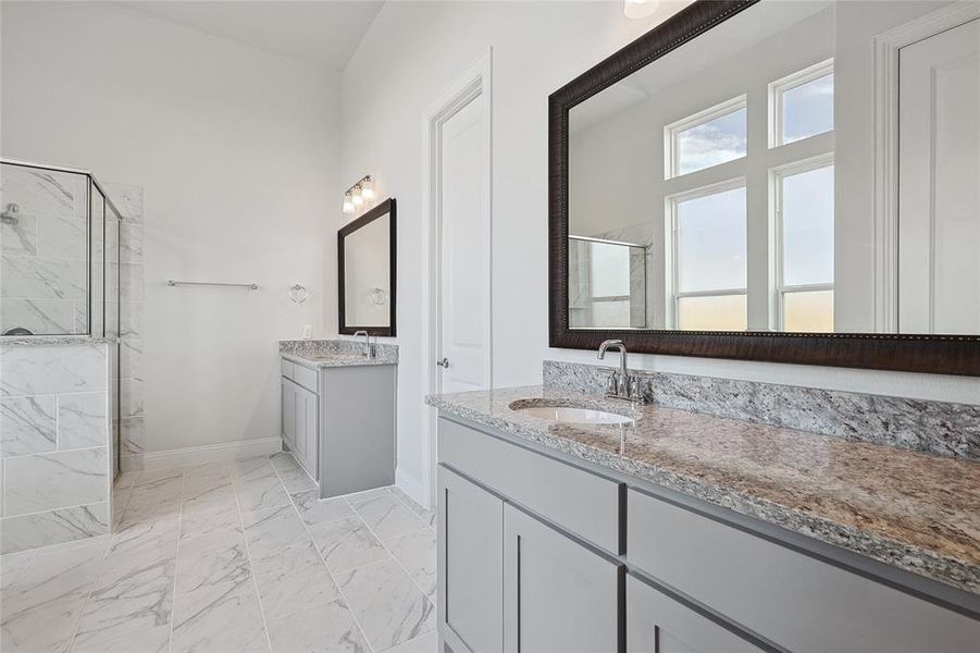 Full bathroom with two vanities, a marble finish shower, and light marble finish floors Full bathroom with two vanities, a marble finish shower, and light marble finish floors