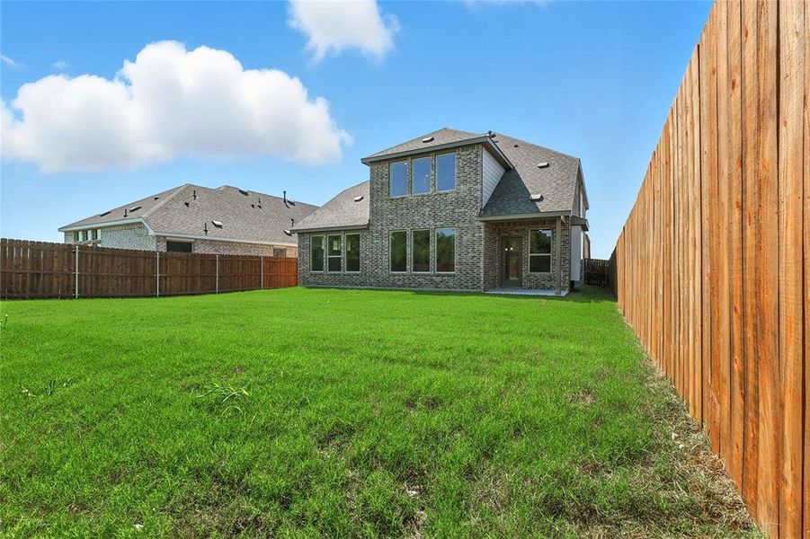 Rear view of property featuring a fenced backyard, brick siding, a patio, and roof with shingles