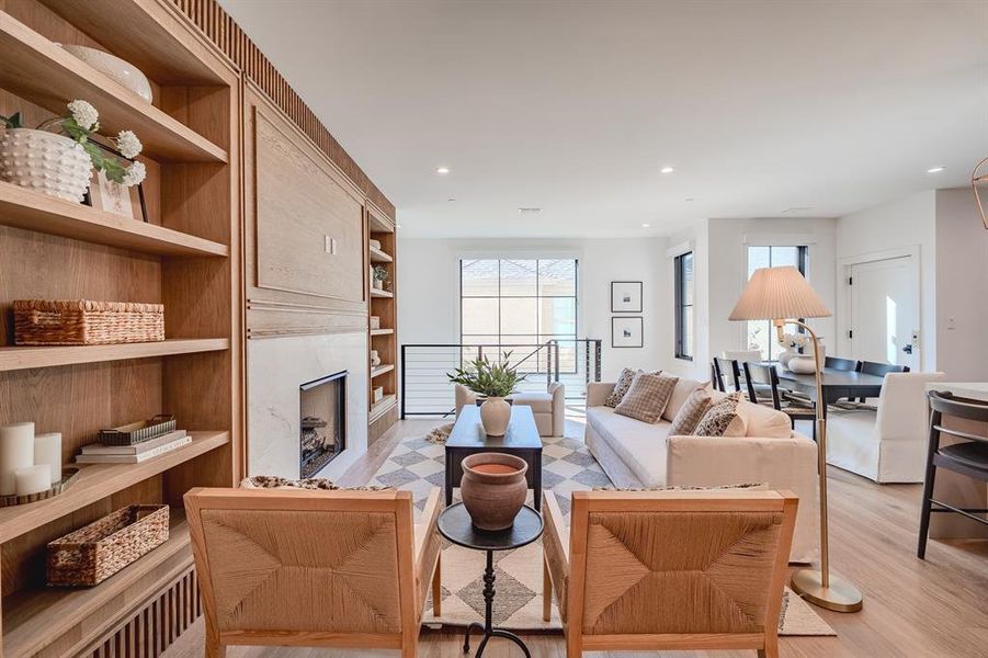 Living room featuring light wood-style flooring, a high end fireplace, recessed lighting, built in shelves, and a barn door Living room featuring light wood-style flooring, a high end fireplace, recessed lighting, built in shelves, and a barn door