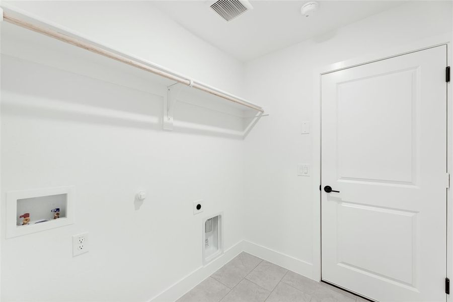 Laundry room with wall-mounted shelf, washer and dryer hookups, and white tile floor Laundry room with wall-mounted shelf, washer and dryer hookups, and white tile floor