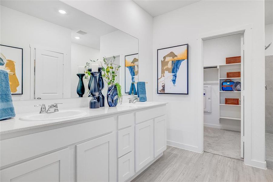 Full bath with a walk in closet, visible vents, a sink, and double vanity