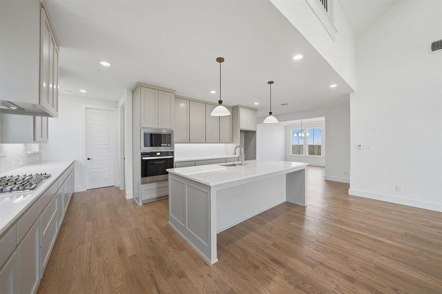 Kitchen with a center island with sink, appliances with stainless steel finishes, light wood-style flooring, pendant lighting, and recessed lighting Kitchen with a center island with sink, appliances with stainless steel finishes, light wood-style flooring, pendant lighting, and recessed lighting
