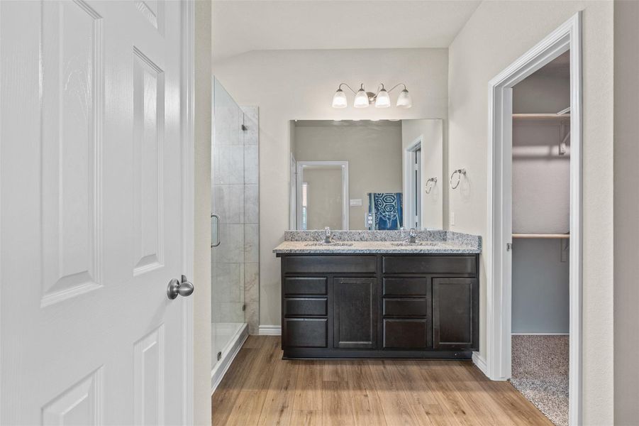 Full bathroom with a stall shower, light wood-style flooring, double vanity, and a spacious closet