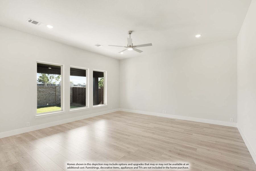Empty living room with light wood floors, ceiling fan, and three windows overlooking backyard Empty living room with light wood floors, ceiling fan, and three windows overlooking backyard