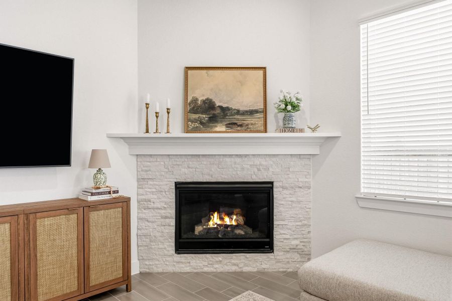 A beautifully crafted gas-log fireplace, framed by a stacked-stone surround and substantial wood mantel, showcases the workmanship and rich natural textures while creating a warm, refined focal point in the living space.