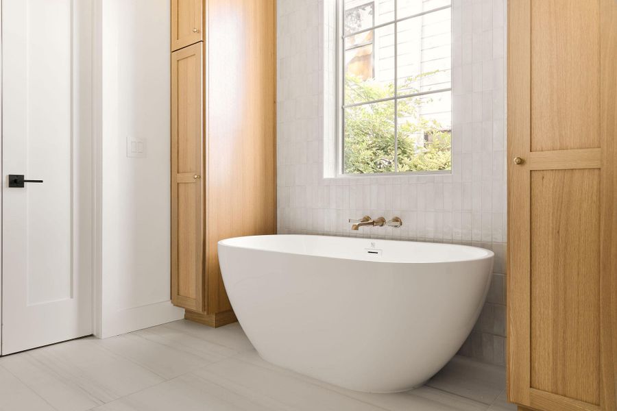 Bathroom with a freestanding tub, tile walls, and tile patterned flooring Bathroom with a freestanding tub, tile walls, and tile patterned flooring