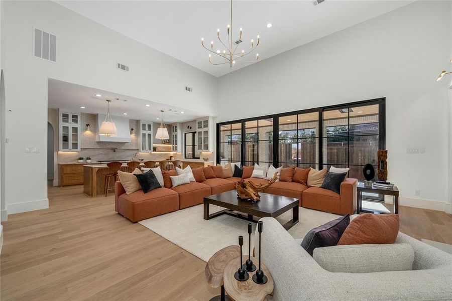 Expansive open-concept space featuring soaring ceilings, a modern chandelier, and wide-plank wood-finish flooring