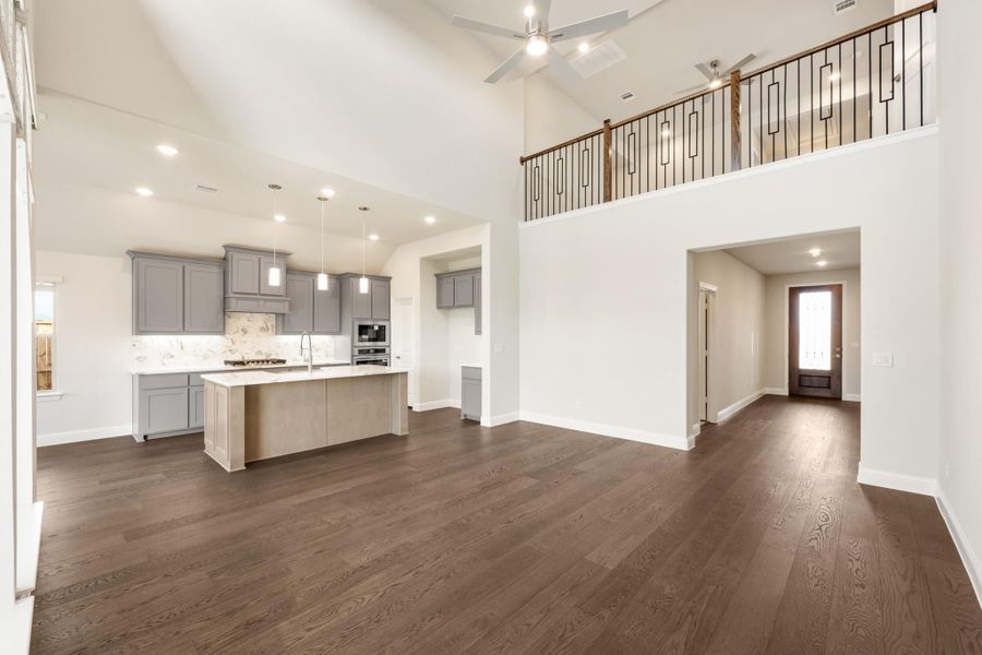 Open-concept living area with vaulted ceiling, dark hardwood floors, and kitchen with gray cabinets and large island Open-concept living area with vaulted ceiling, dark hardwood floors, and kitchen with gray cabinets and large island